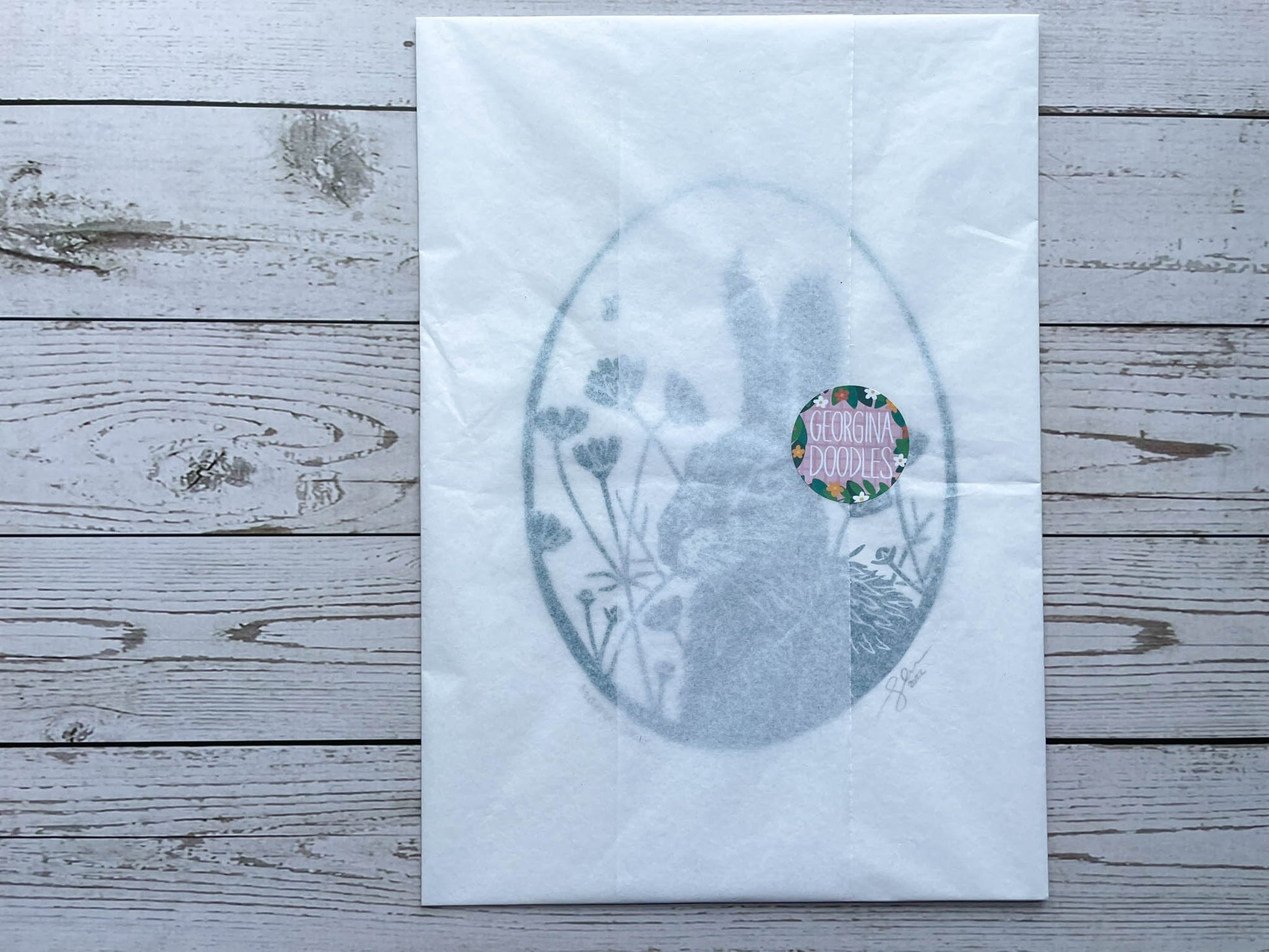 The hare lino print wrapped in white tissue paper and secured with a georgina doodles sticker