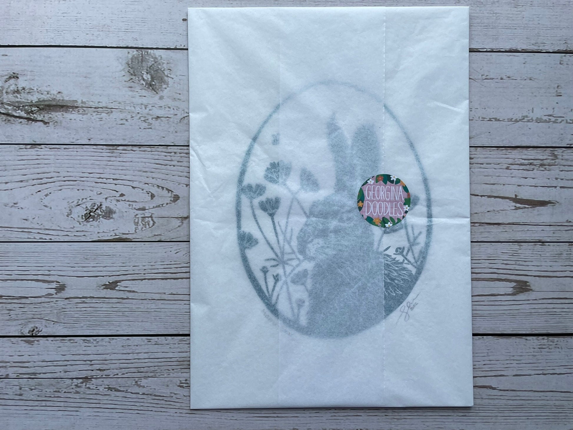A print wrapped in tissue paper and secured with a georgina doodles sticker