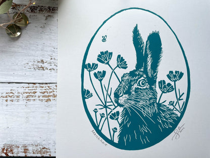 An oval lino print of a hare surrounded by flowers printed on A4 paper