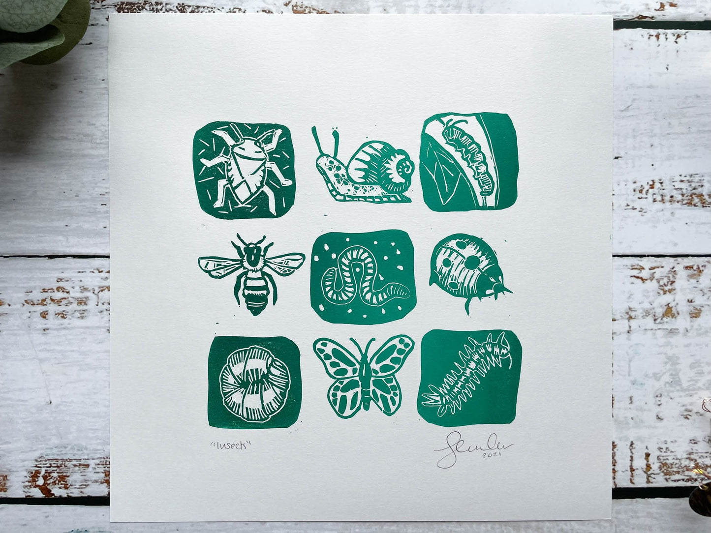 A lino print of a 3 x 3 grid of mini-beasts in a dark to light green gradient