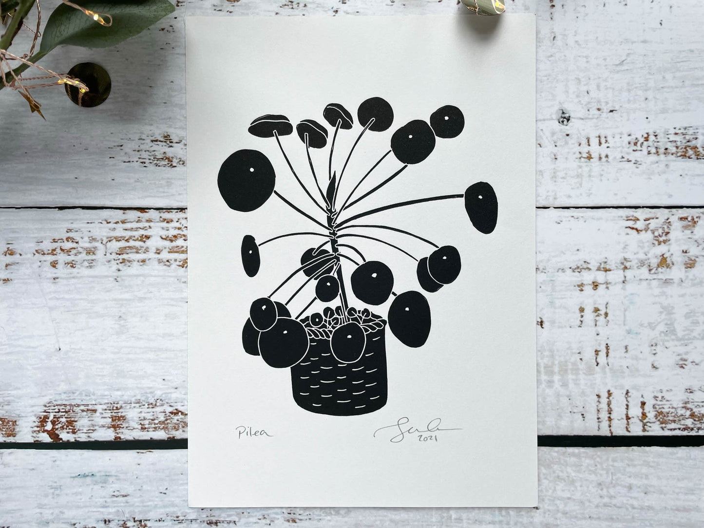 A black A5 lino print of a pilea plant