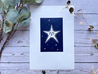 A lino print of a star with a face and surrounded by stars on A4 paper