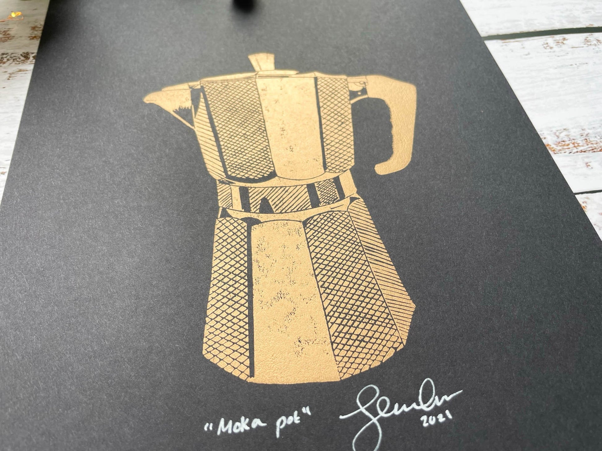 A lino print of a coffee moka pot in copper on black paper