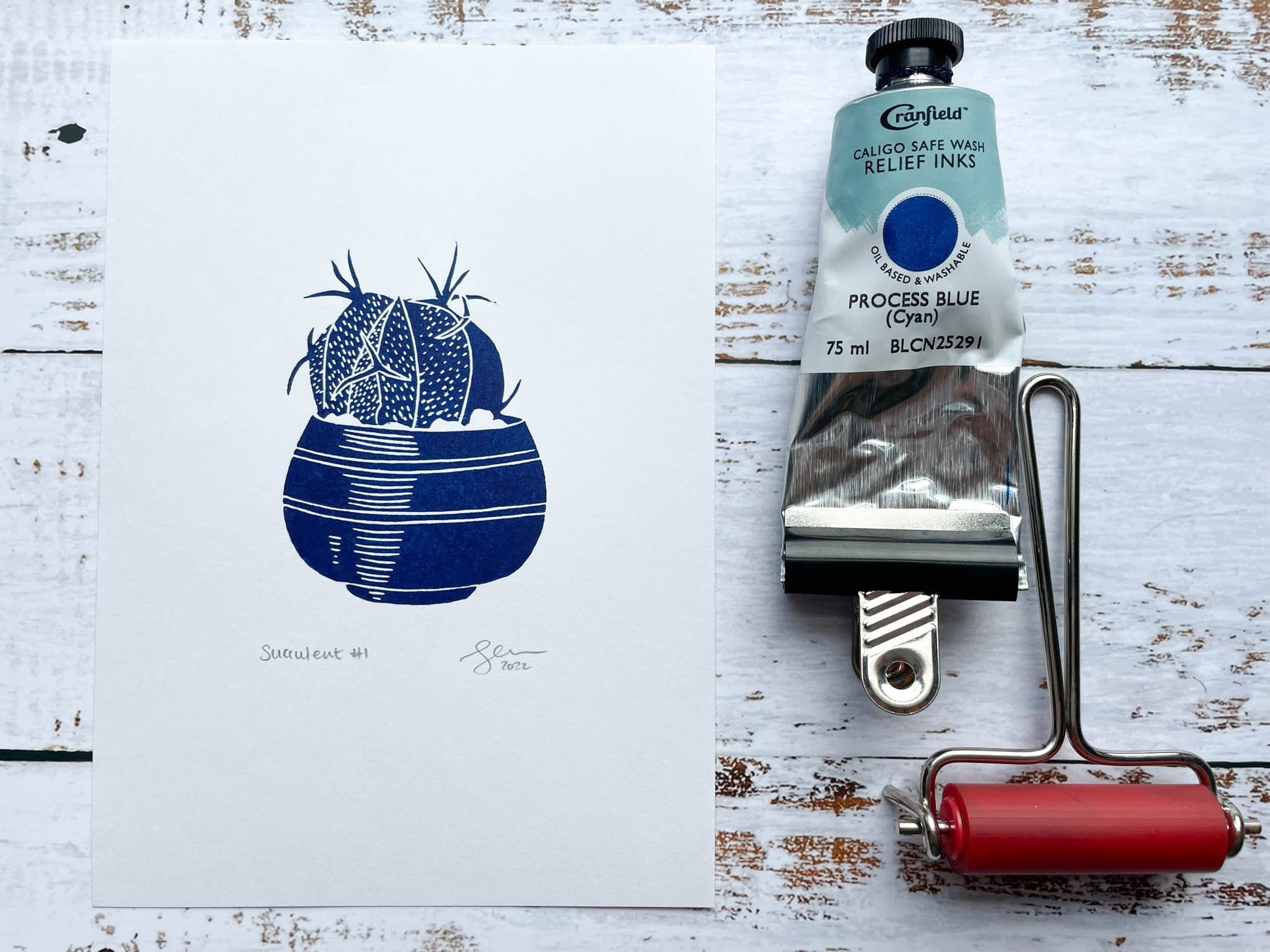A small blue lino print of a little potted succulent