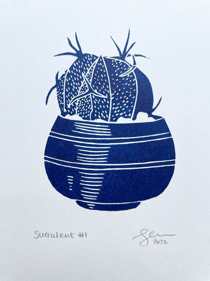 A small blue lino print of a little potted succulent