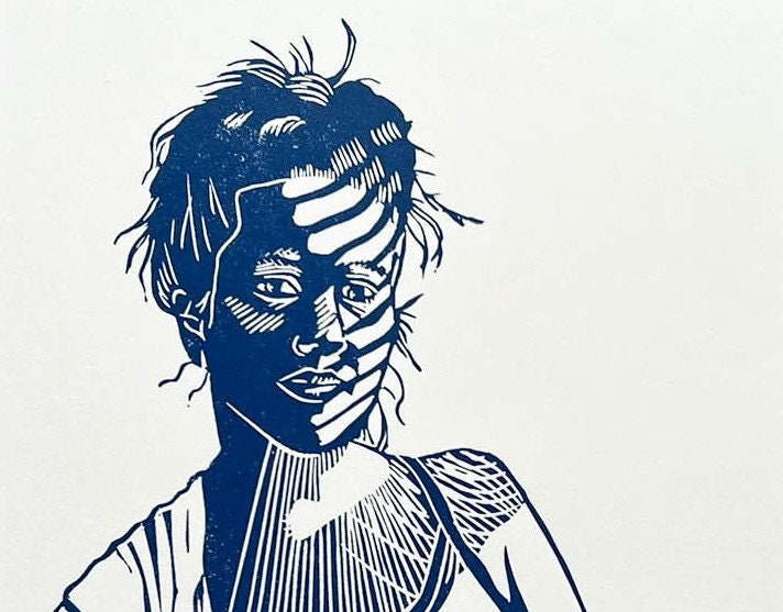 A blue lino print of a mother breastfeeding her baby in a ring sling with sunlight across her face through the blinds.