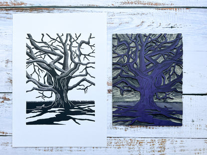 A lino print of a gnarly oak tree with dramatic shadows next to the carved lino block