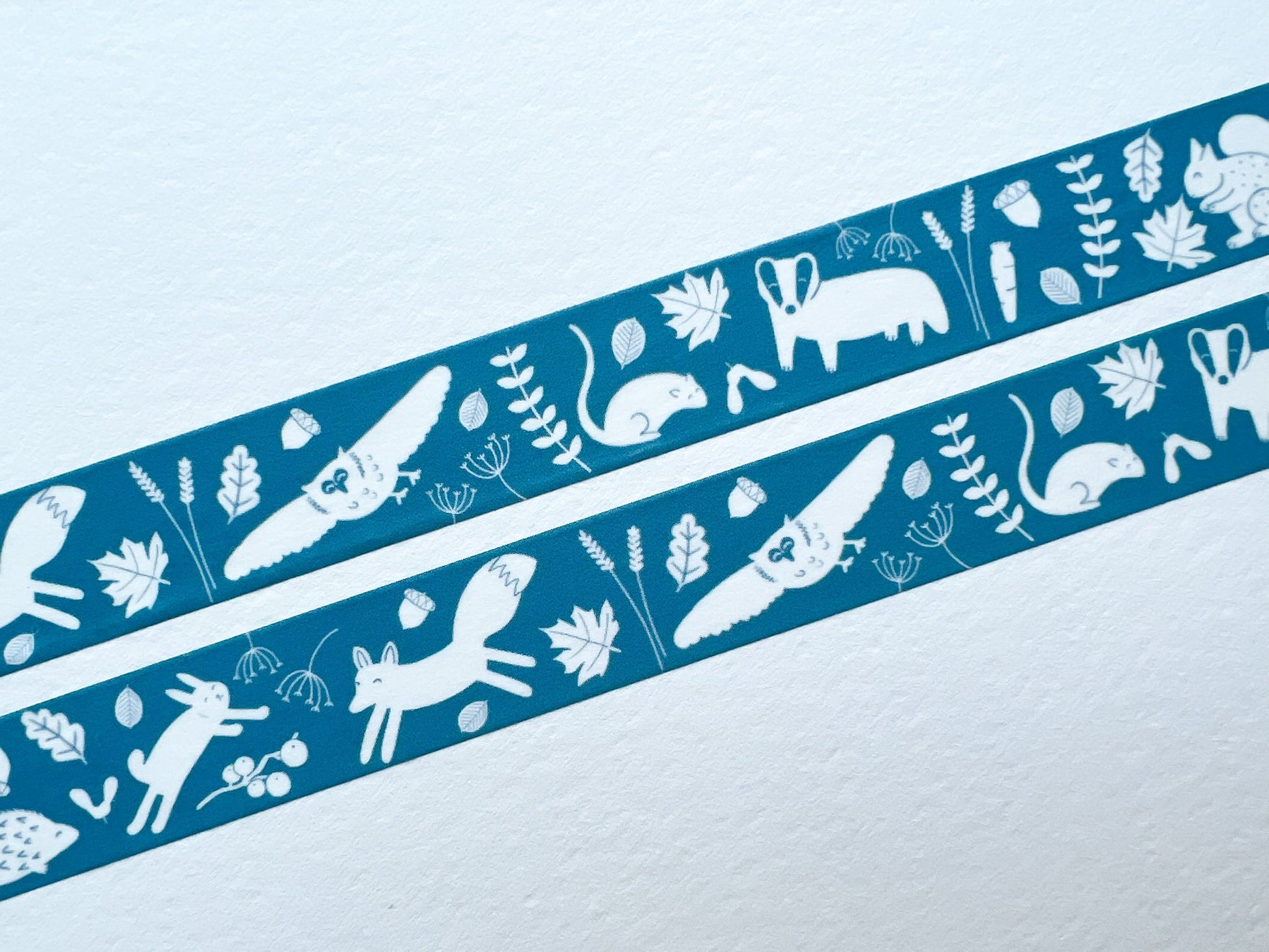 A blue/teal coloured washi tape with white woodland illustrated animals on