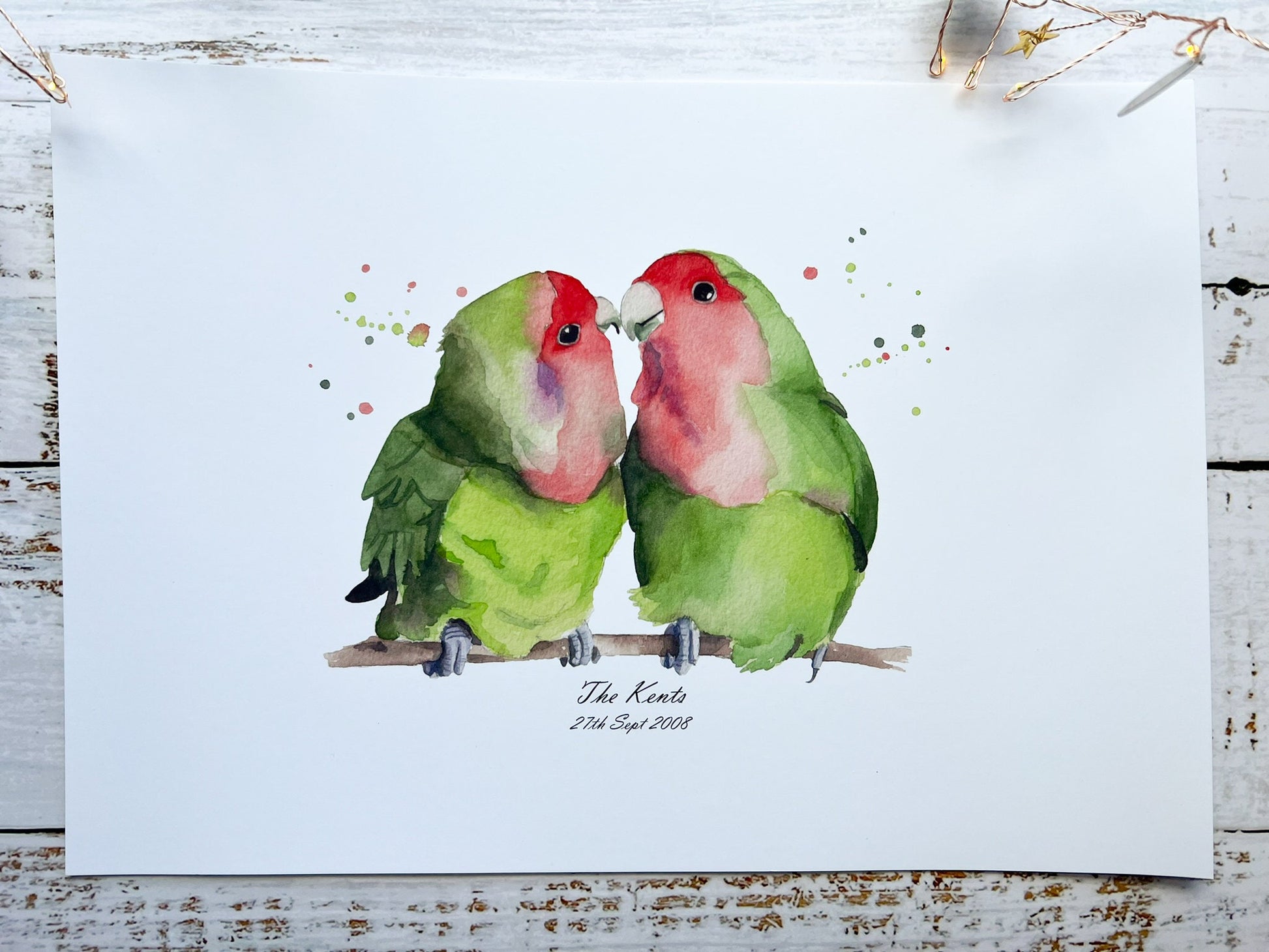 A watercolour print of two lovebirds, underneath is the surname of a couple and their date they got married