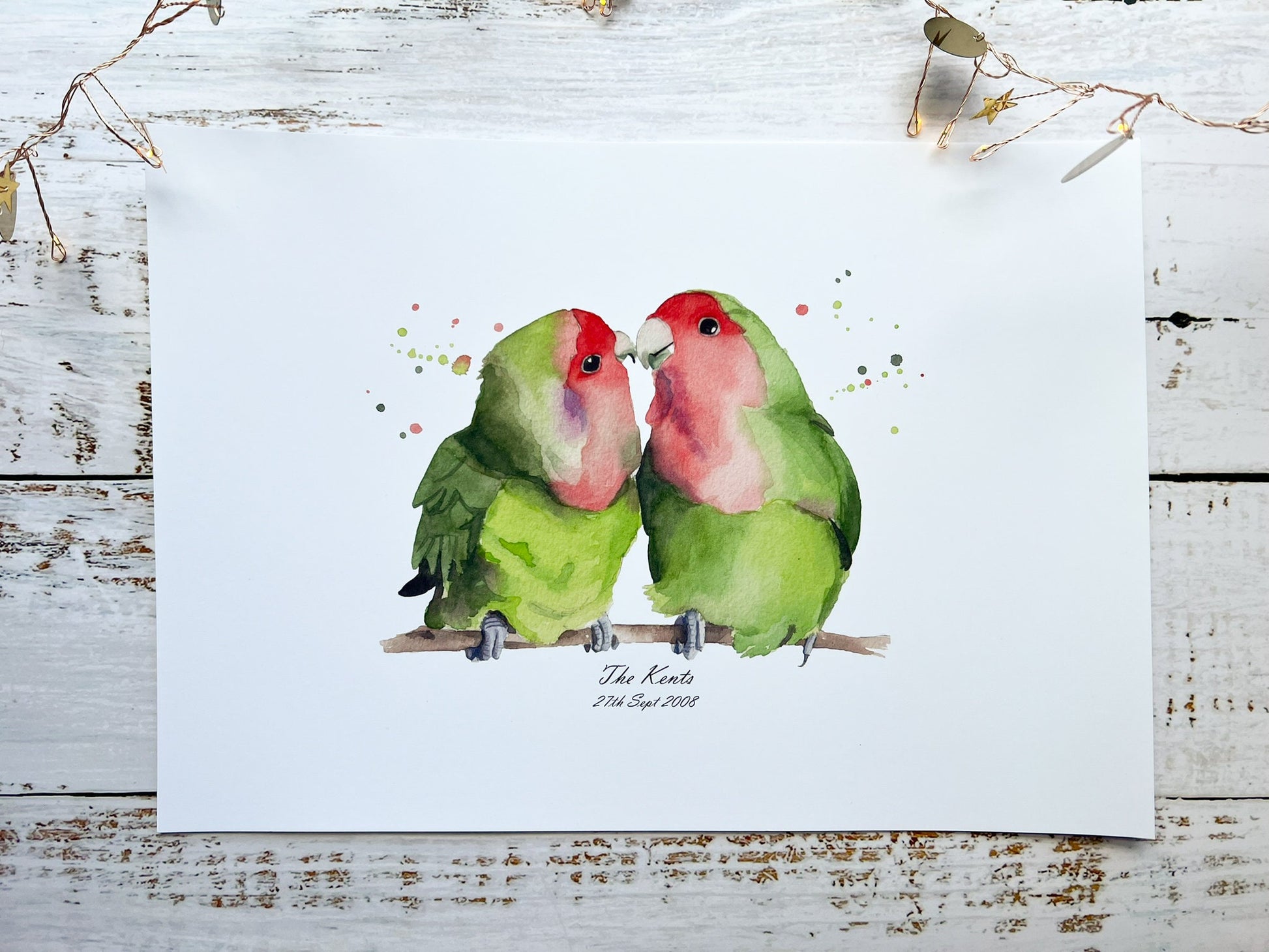 A watercolour print of two lovebirds, underneath is the surname of a couple and their date they got married